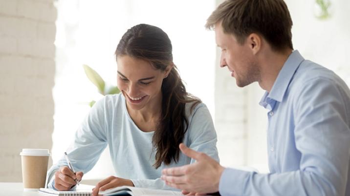 Two people working together taking notes