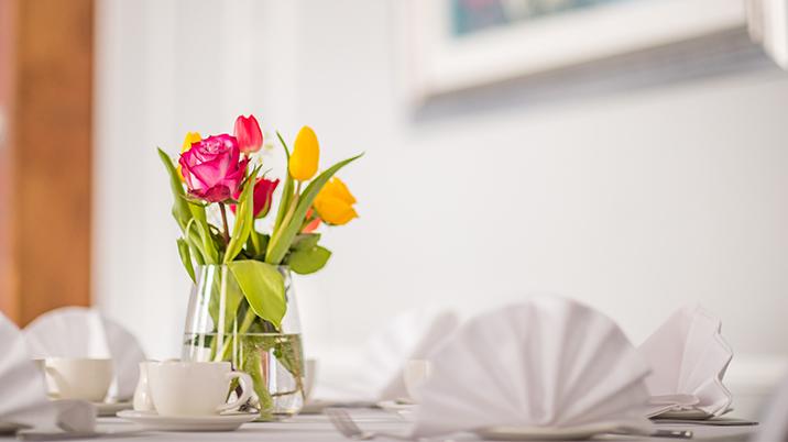 A dining table set up with a vase in the middle