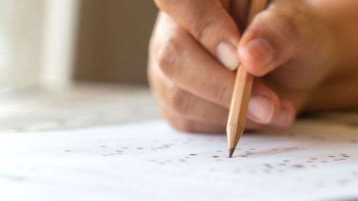 Person with pencil filling out examination