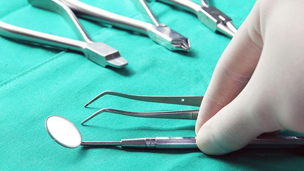 A hand with glove picking up dentistry utenstils