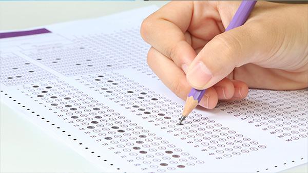 Hand with pencil filling out examination paper