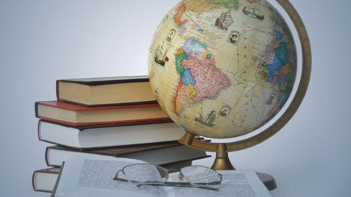 Books piled up stood next to a globe