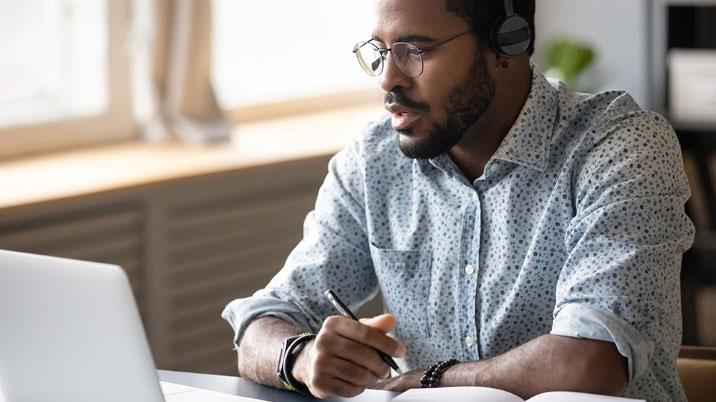 Person sitting at a laptop with headphones on