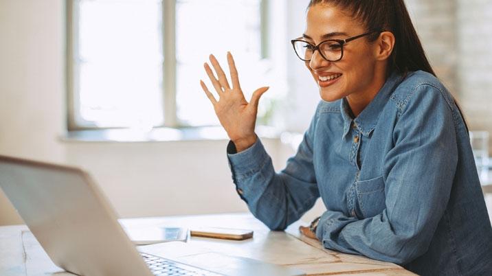 Person in front of a laptop waving to the screen