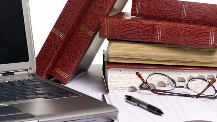 Books, a laptop and some glasses on top of a notepad