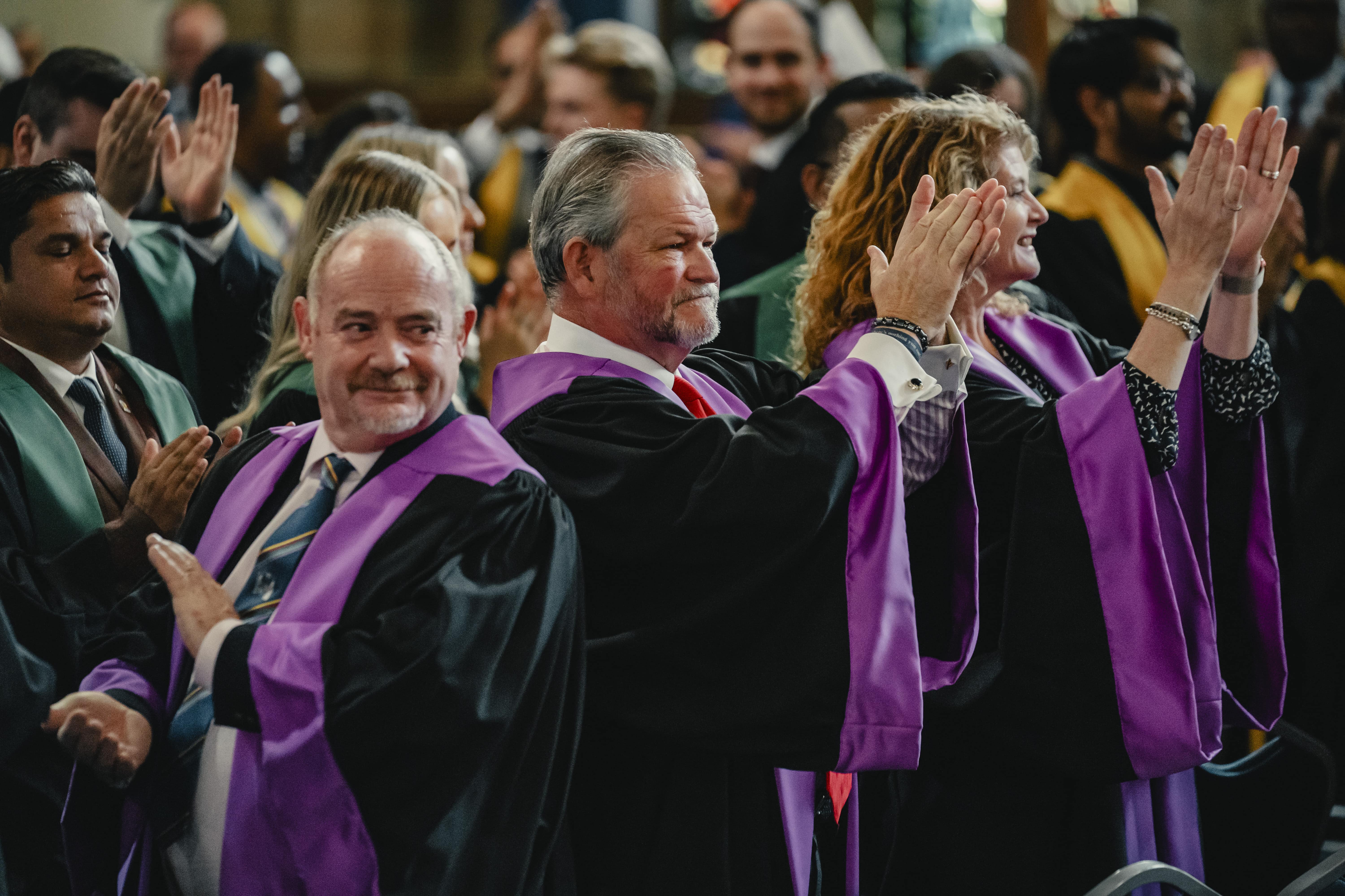 Members of the Faculty of Podiatric Medicine in ceremonial robes applaud during a formal event at the College