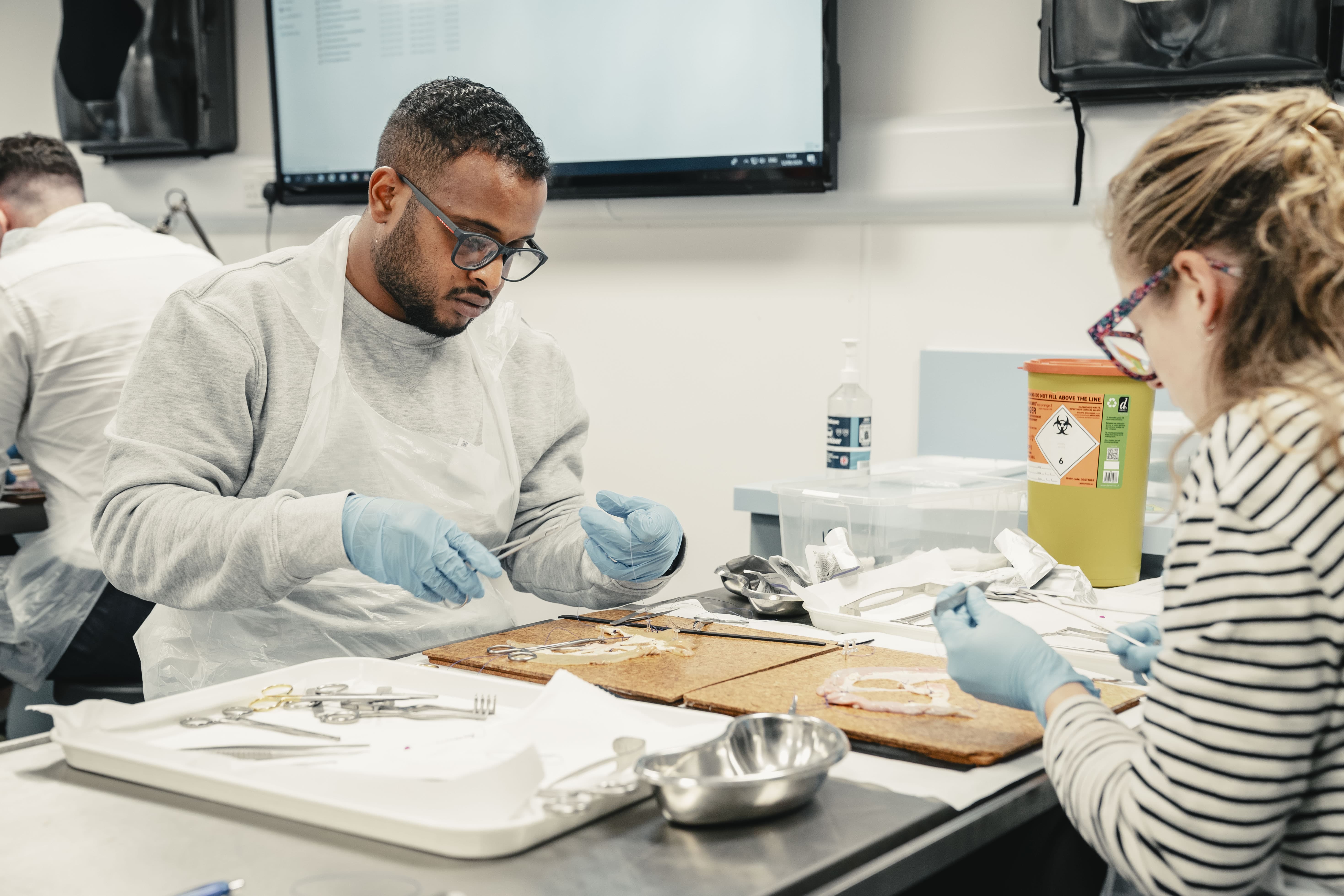 two people participating in basic surgical skills course