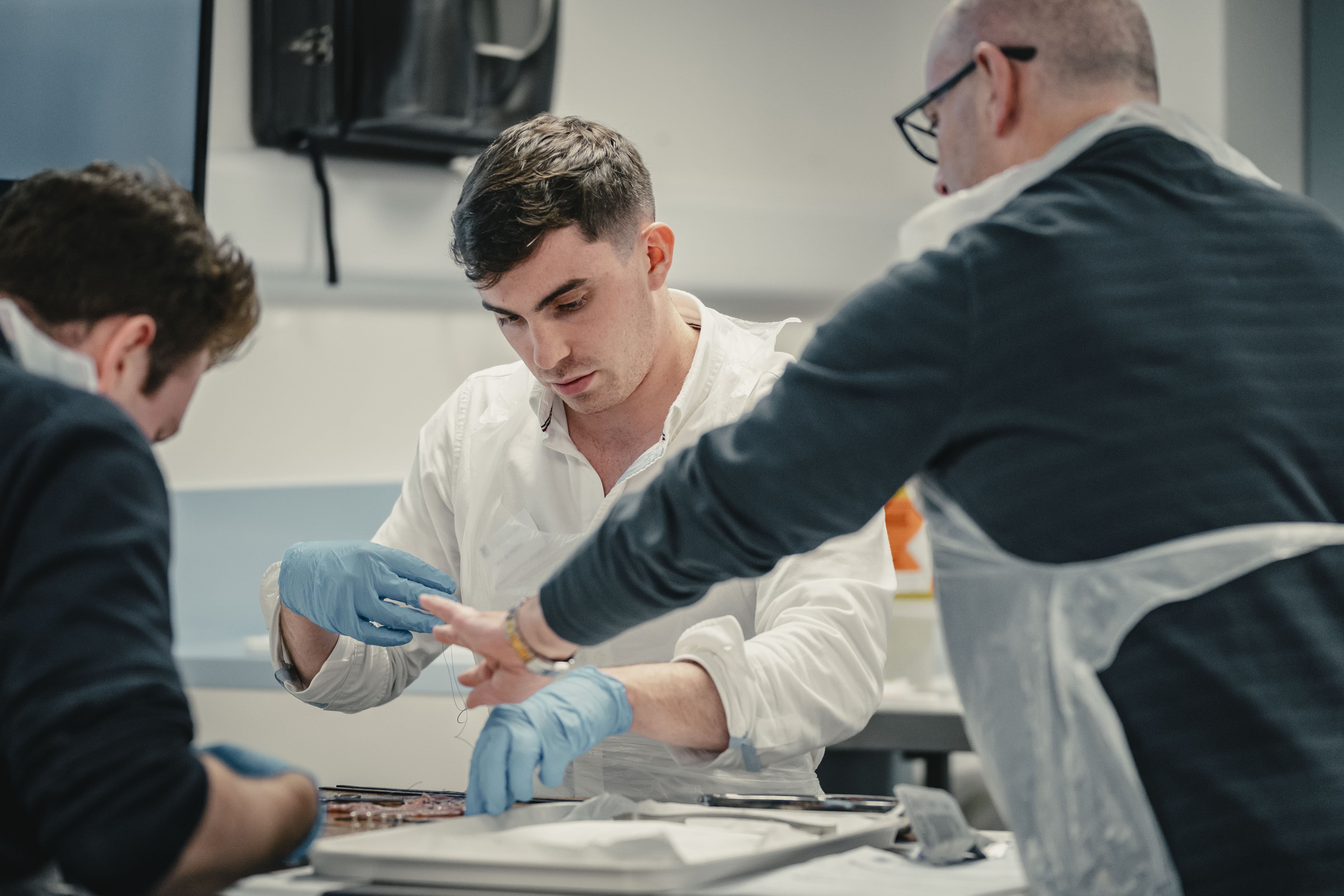 someone being supported through the basic surgical skills course