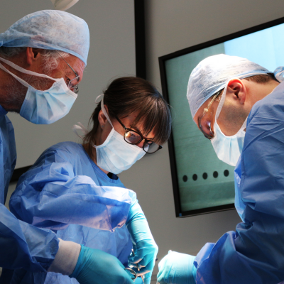 Three people in surgical dress at a casc course