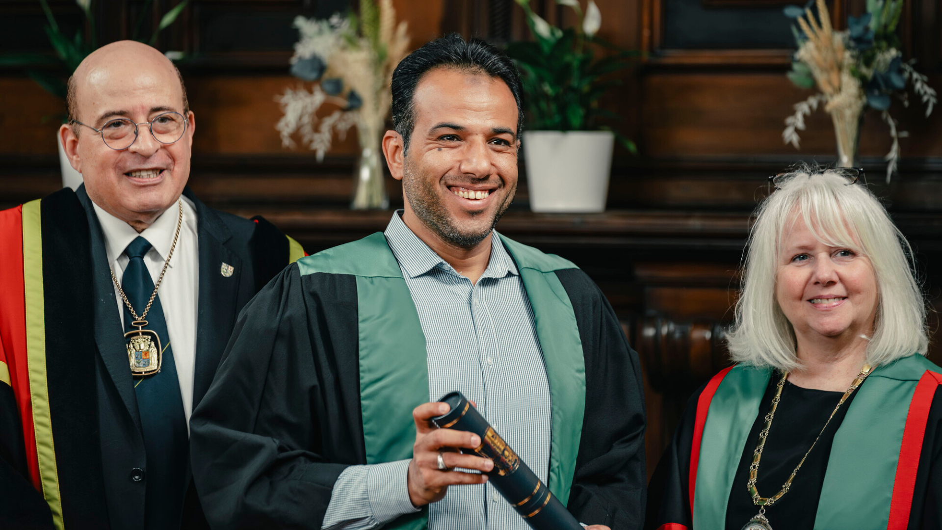Three people celebrating at a diploma ceremony