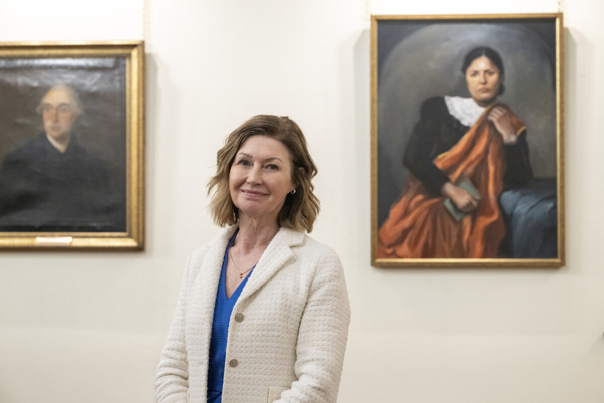Professor Jackie Taylor standing in front of portrait of our College's first female Fellow Jamini Sen