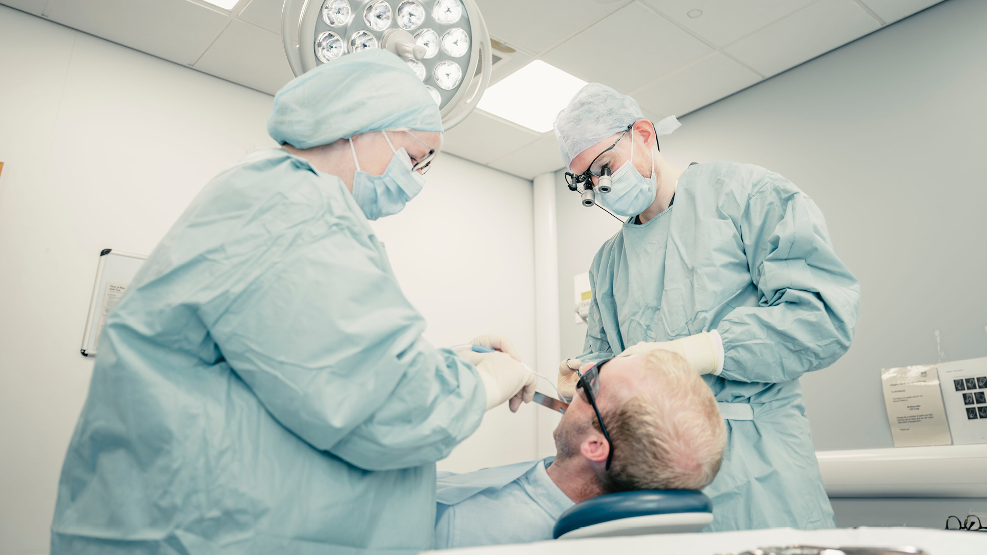 Dental patient in a chair for procedure with two dental professionals
