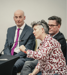 a woman talking on a panel at a conference 
