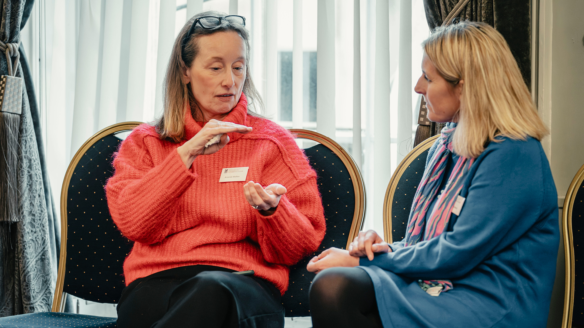 Two female participants sitting together in the College, in conversation 