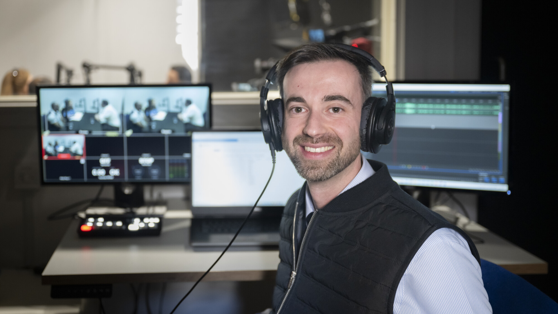 Colleague sat at a sound desk with headphones on