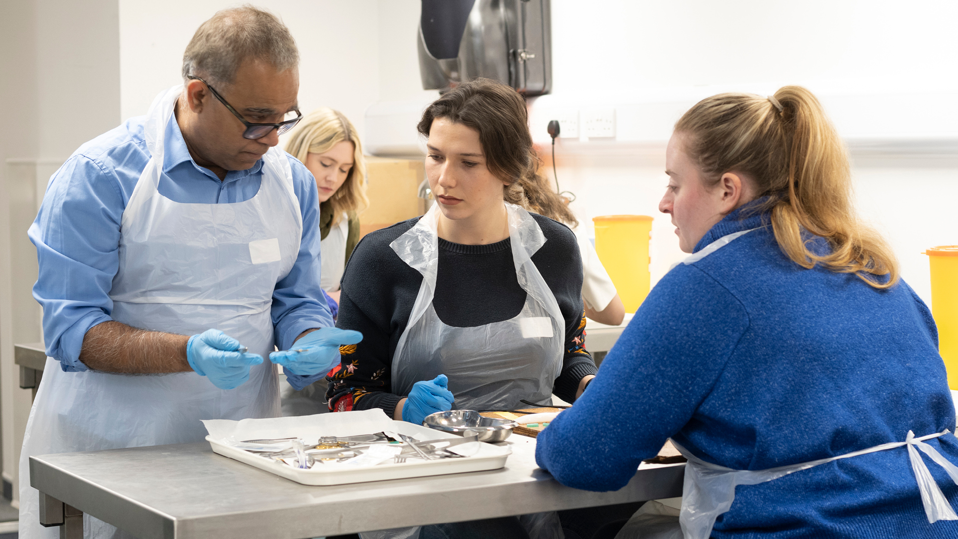 Clinician showing two participants a surgical procedure. 