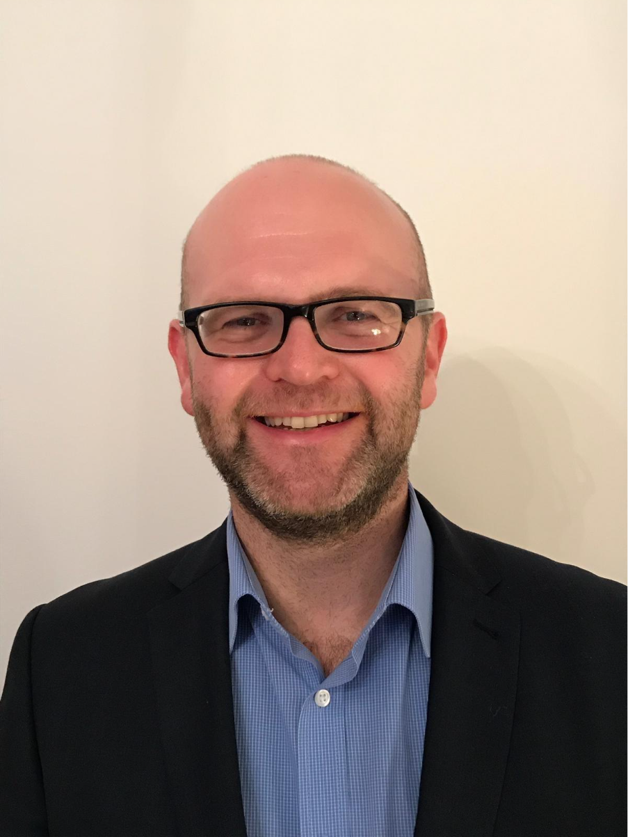 A person wearing glasses and a suit
AI-generated content may be incorrect.